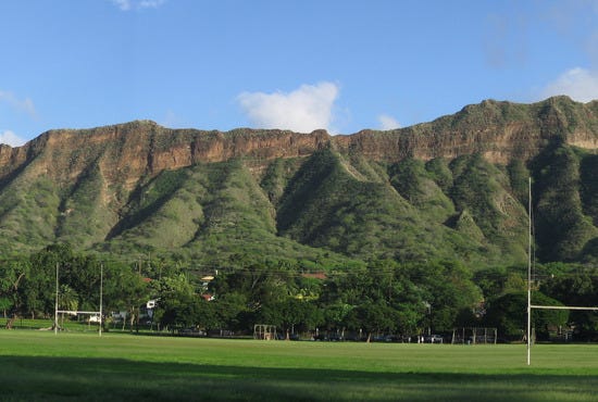 Kapi'olani Park, with its broad green lawn, rises to meet Diamond Head.
