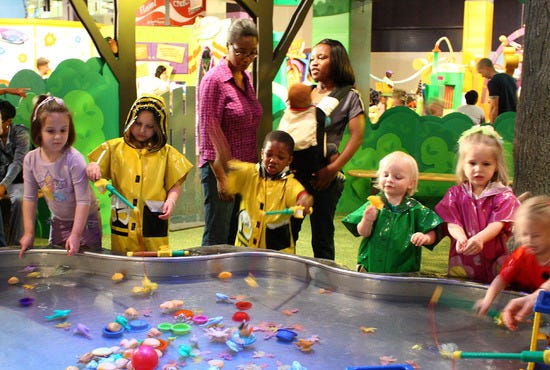 Children in raincoats enjoying the water table exhibit at Imagine It! The Children's Museum of Atlanta.