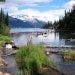 A glacier lake runs clear through evergreens and mountain peaks.