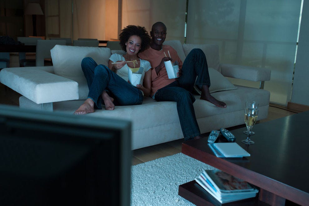 Couple watching TV and eating food on the couch