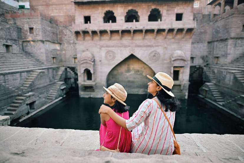 Rear view of tourist mother and daughter sitting at step well