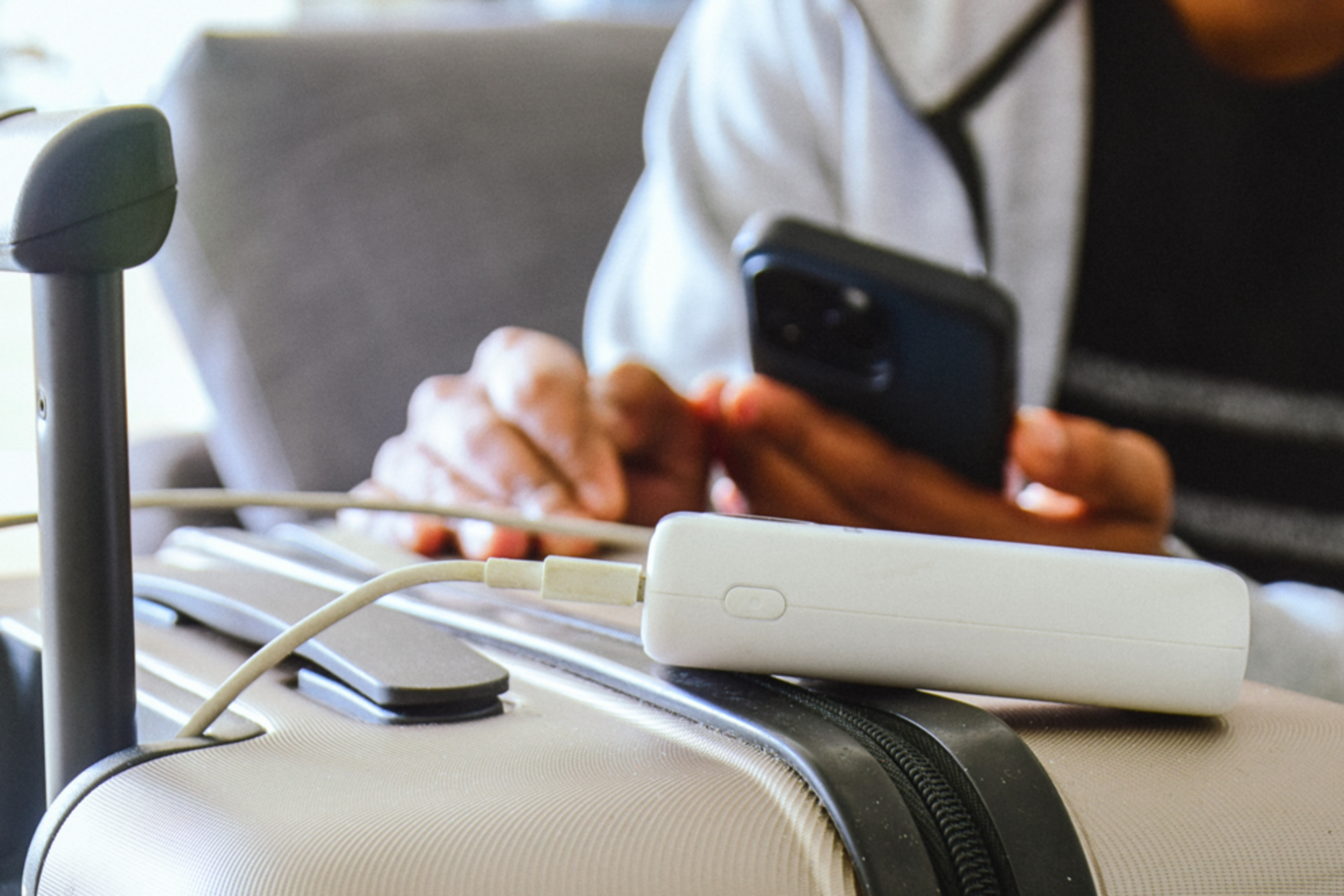 Cropped image of a man waiting in airport lounge charging his phone using power bank before departure.